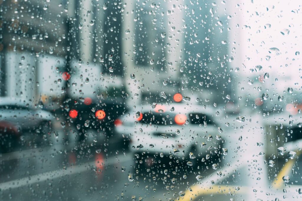 Rain on a car window with wet-road traffic lights blurred in the background