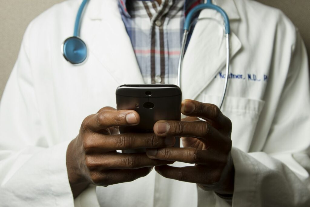 Doctor in white coat using a smartphone during a medical consult